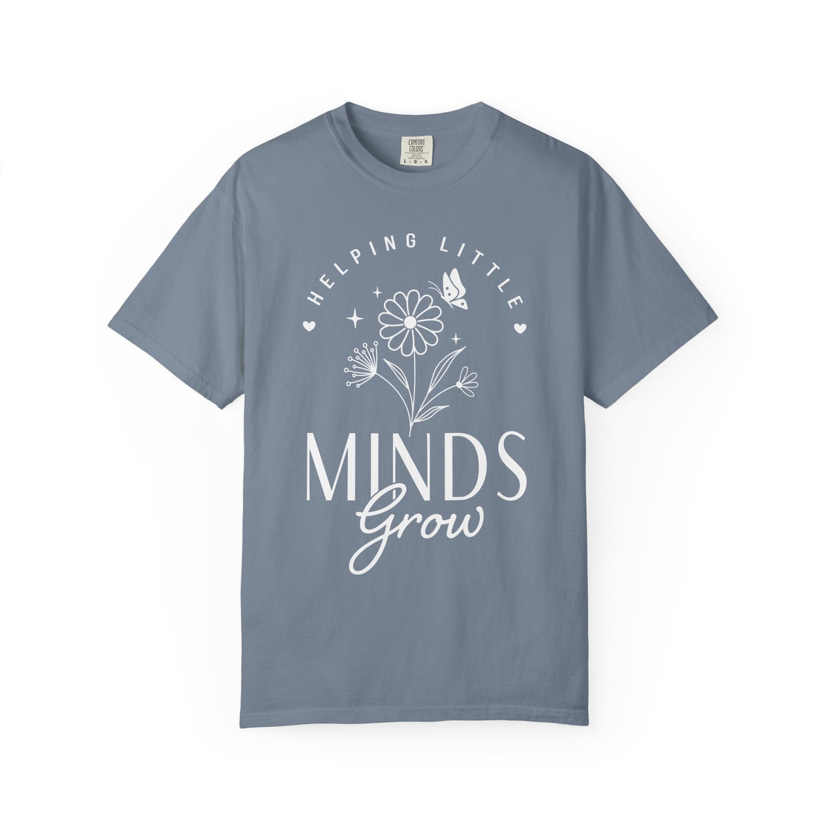 A gray blue crewneck t-shirt with a white graphic print on the front that reads 'HELPING LITTLE MINDS Grow' with a flower and butterfly illustration, shown on a plain gray blue background.