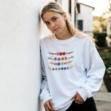 Woman wearing a white sweatshirt with '100 Days of School' text, standing against a light-colored wall.