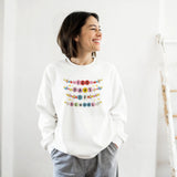 Person wearing a white sweatshirt with colorful text design on a plain background