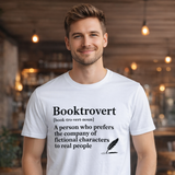 Man wearing a white t-shirt with 'Booktrovert' definition and graphic in a casual setting.