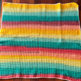Colorful striped knitted blanket on a wooden surface