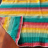 Colorful striped crocheted blanket on a wooden surface