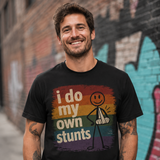Man wearing a black t-shirt with a colorful graphic and text, standing in front of a graffiti-covered wall.