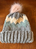 Knitted beanie with a pom-pom on a wooden surface