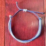 Bracelet with blue and white strings on a wooden surface
