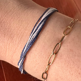 Close-up of a wrist wearing two bracelets on a wooden floor.