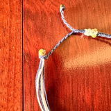 Braided bracelet with yellow beads on a wooden surface