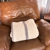 Brown leather chair with a textured white pillow on it