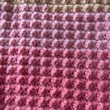 Close-up of a knitted fabric with a waffle pattern in pink and brown.