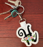 Keychain with floral design and initials on a wooden surface