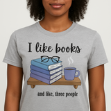 Person wearing a gray t-shirt with a graphic design and text 'I like books and like, three people'.