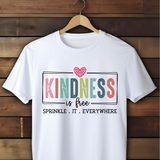 White t-shirt with 'Kindness is free, sprinkle it everywhere' text on a wooden background
