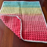 Colorful crocheted blanket on a wooden floor