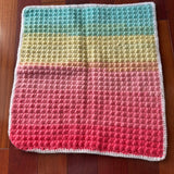 Colorful crocheted blanket on a wooden floor