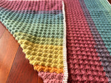 Colorful crocheted blanket on a wooden surface
