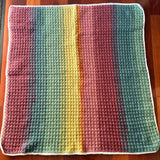 Multicolored crocheted blanket on a wooden surface
