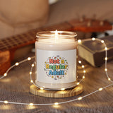 Candle with a 'Not a Regular Adult' label on a wooden coaster with fairy lights and a guitar in the background.
