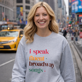 Woman wearing a gray sweatshirt with colorful text on a city street.