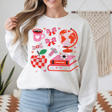 Person wearing a white sweatshirt with colorful graphics in a cozy room.