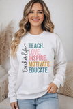 Woman wearing a white sweatshirt with colorful text 'TEACH. LOVE. INSPIRE. MOTIVATE. EDUCATE.'