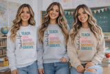 Three women wearing sweaters with motivational teacher quotes in a classroom setting.