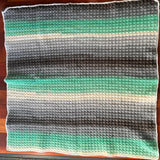 Striped crochet blanket on a wooden floor