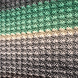 Close-up of a textured fabric with green, beige, and gray stripes.