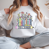Person wearing a white sweatshirt with a colorful book design and 'Mrs. Jones' text.