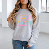Person wearing a gray sweatshirt with colorful text in a bright room