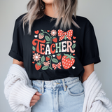 Person wearing a black t-shirt with 'Teacher' design against a plain background
