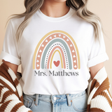 Person wearing a white t-shirt with a rainbow design and text, against a beige background