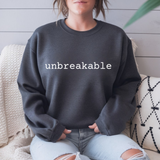 Person wearing a dark gray sweatshirt with 'unbreakable' text, sitting on a couch.